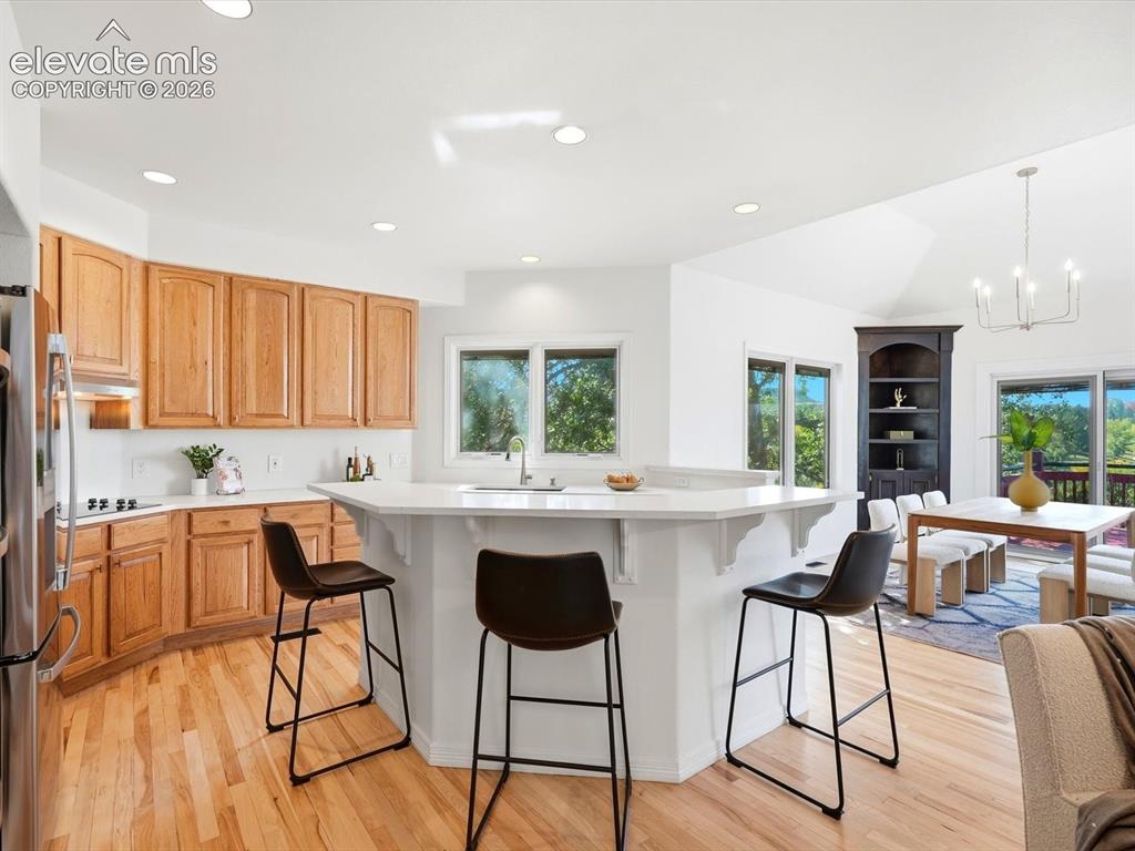Image 8 of 48: Kitchen featuring light-tone wood cabinetry, solid-surface peninsula with i