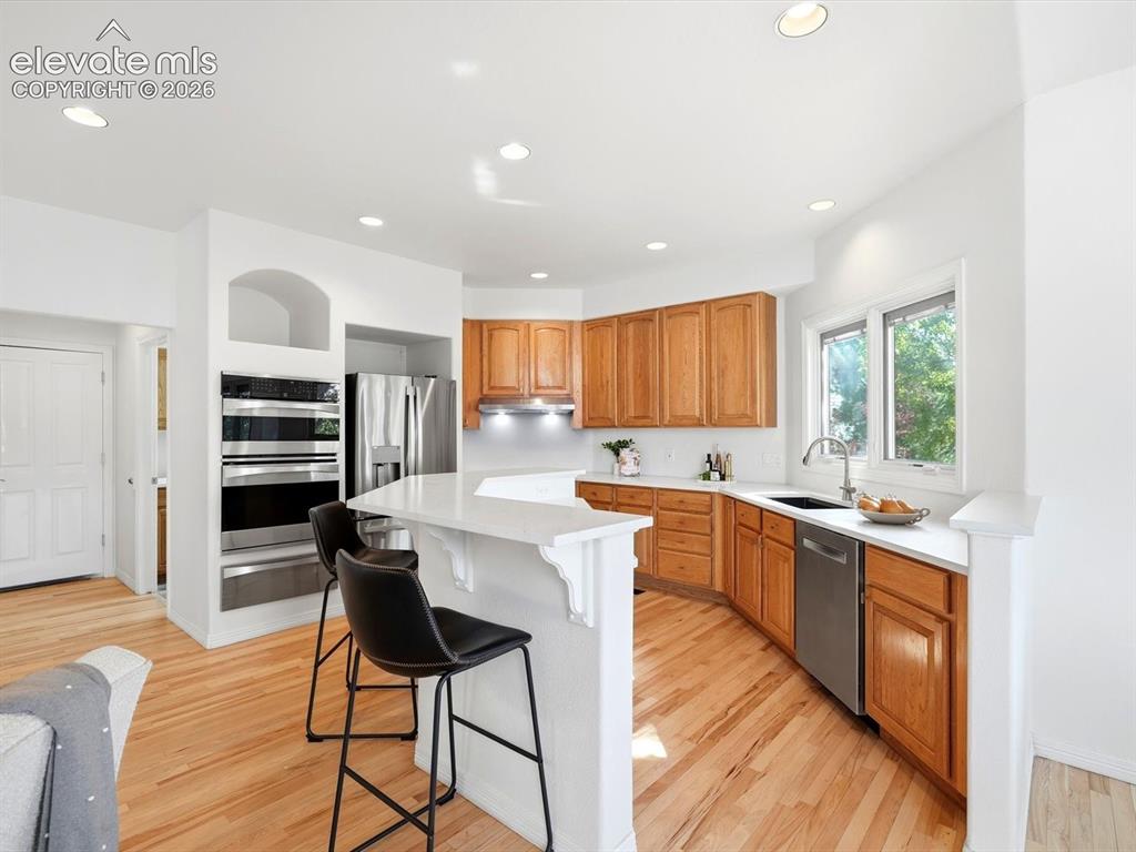 Image 9 of 48: Kitchen featuring wood cabinetry, solid-surface countertops, built-in doubl