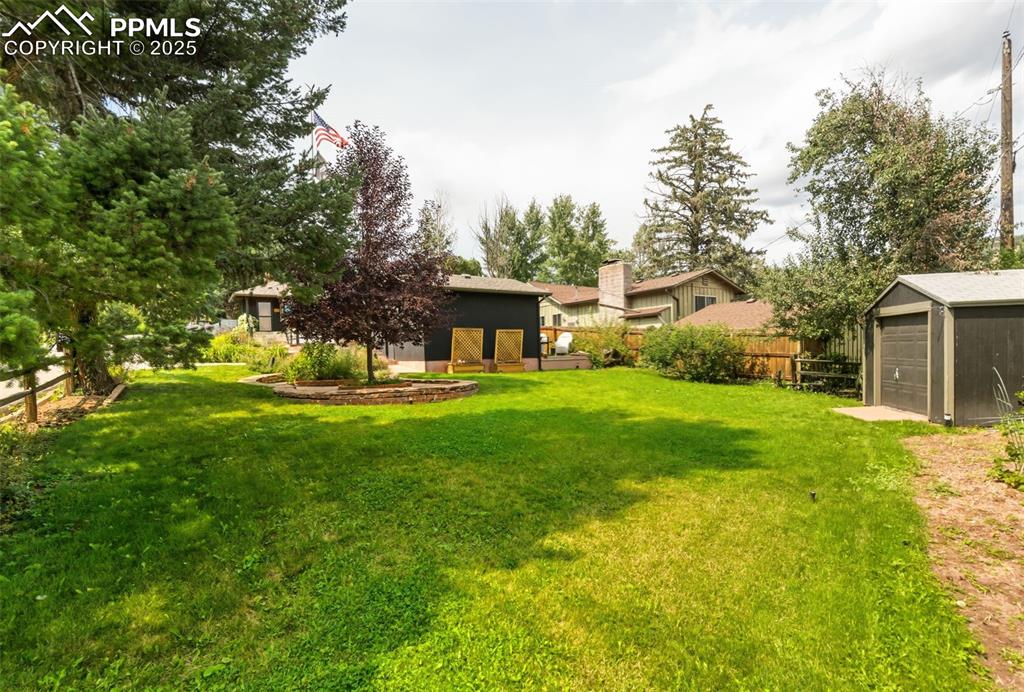 Image 37 of 49: Side/back yard with extra shed and pear tree