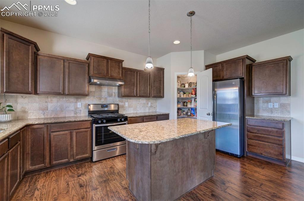 Image 13 of 46: Kitchen featuring stainless steel appliances, a center island, dark wood-st