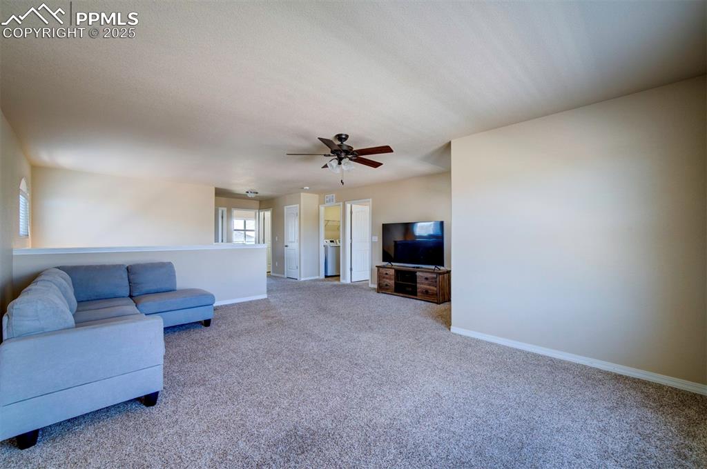 Image 19 of 46: Living area with carpet floors and a ceiling fan