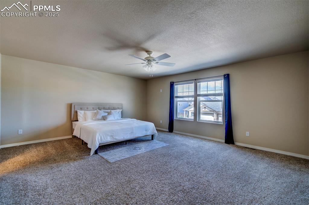 Image 23 of 46: Carpeted bedroom with a textured ceiling and ceiling fan