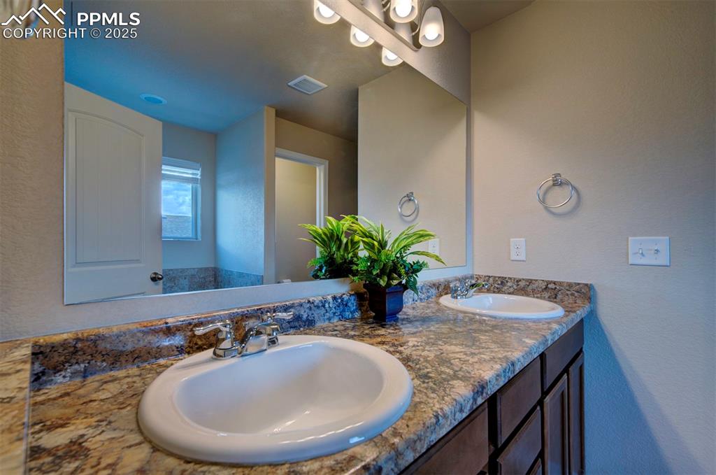 Image 25 of 46: Bathroom featuring double vanity and a textured wall