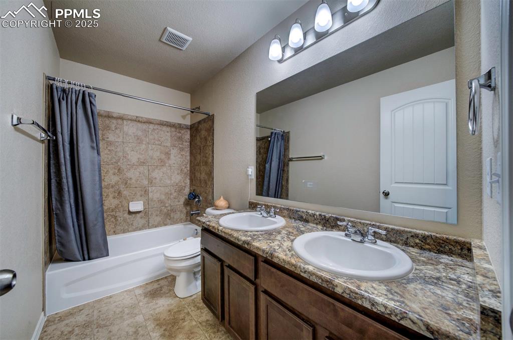 Image 32 of 46: Full bath with shower / tub combo with curtain and double vanity