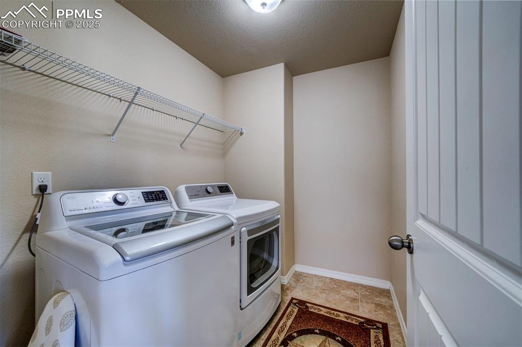 Image 33 of 46: Laundry room featuring washing machine and clothes dryer and a textured cei