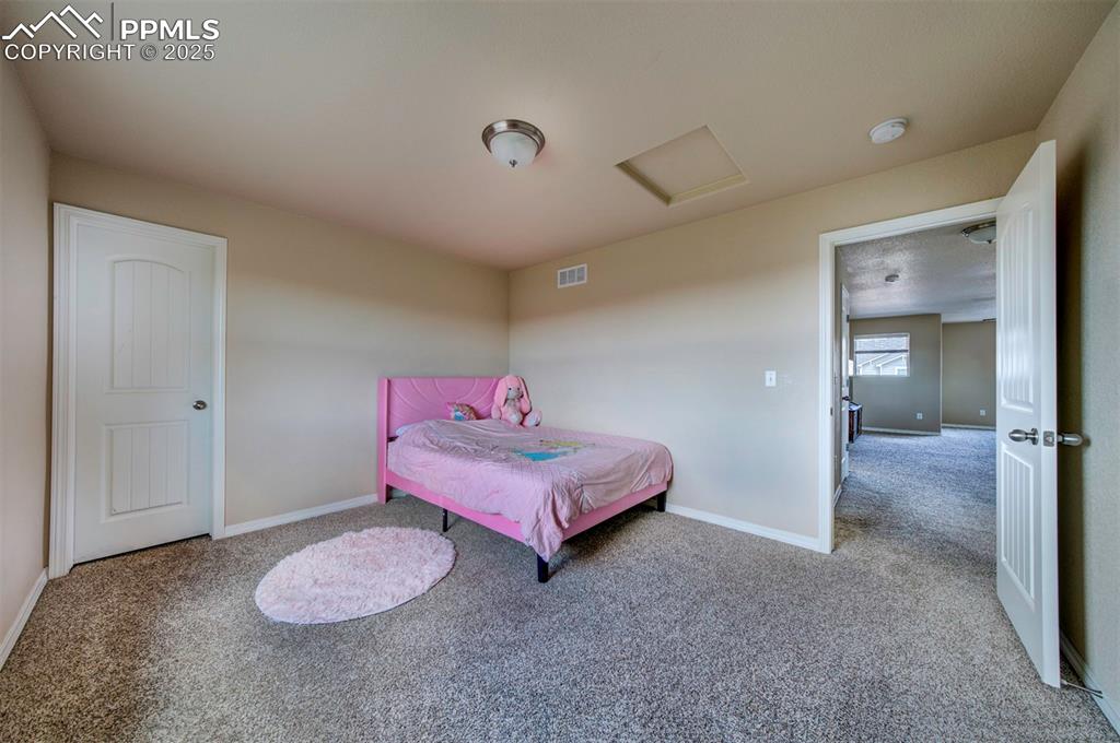 Image 35 of 46: Carpeted bedroom with attic access and baseboards