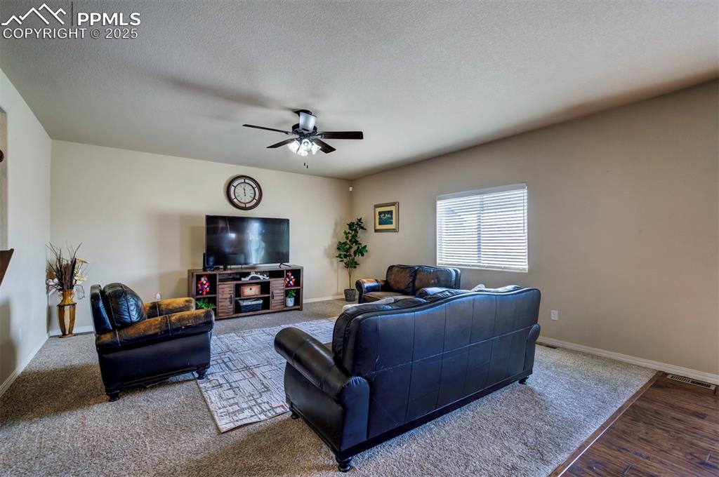 Image 8 of 46: Living area featuring a ceiling fan, wood finished floors, and a textured c