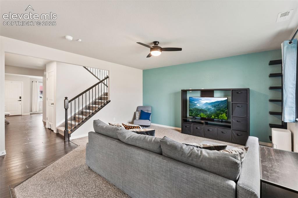 Image 12 of 42: Open-concept living space with dark wood-finish flooring, a carpeted living