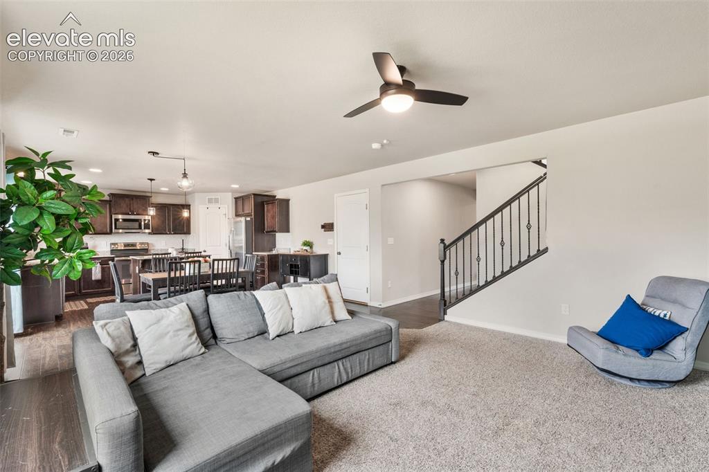 Image 13 of 42: Open-concept living area featuring a ceiling fan, dark wood-finish flooring