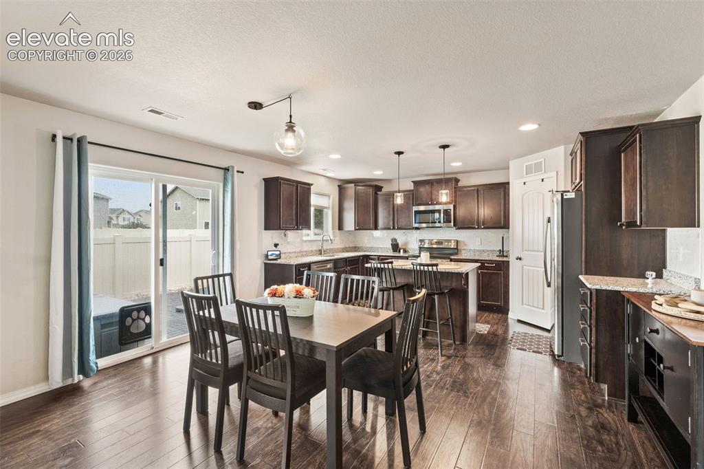 Image 14 of 42: Open-concept kitchen and dining area featuring wood-finish flooring, dark w