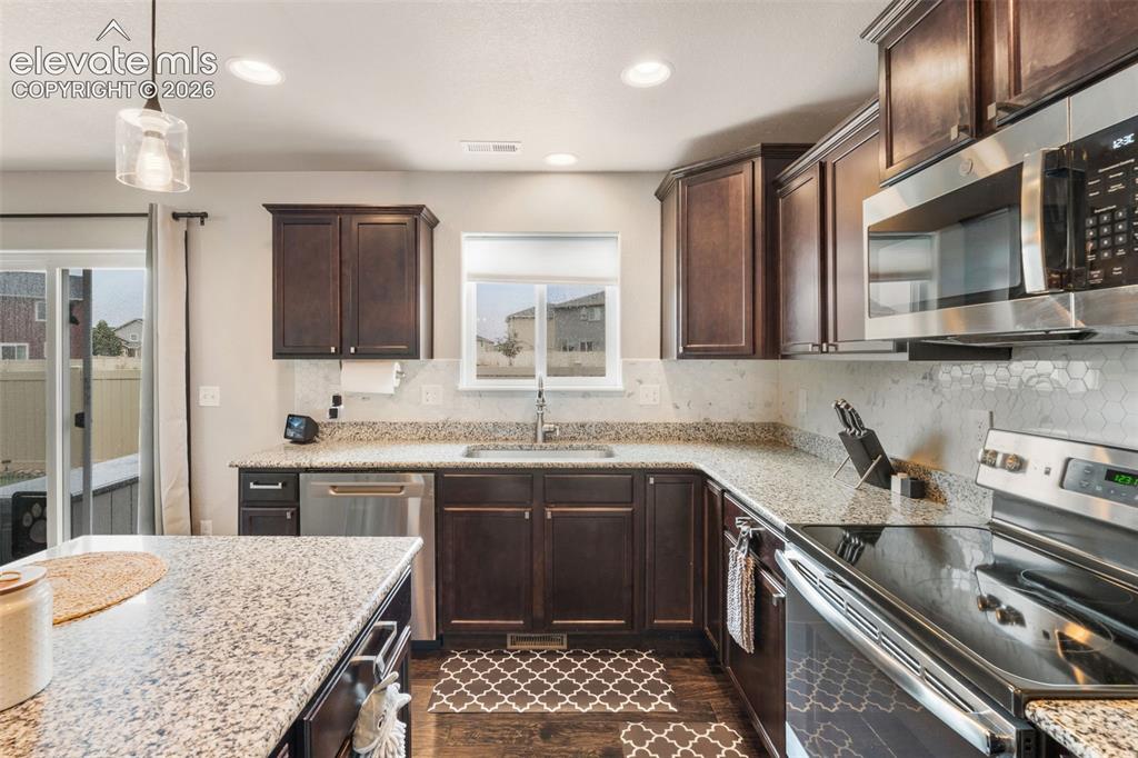 Image 18 of 42: Kitchen featuring dark wood cabinetry, light granite countertops, stainless