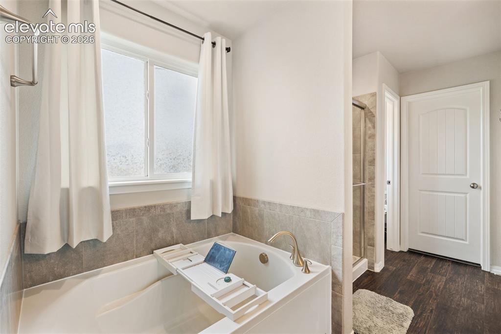 Image 27 of 42: Soaking tub with brass-finish fixtures, a tiled surround, and a privacy win
