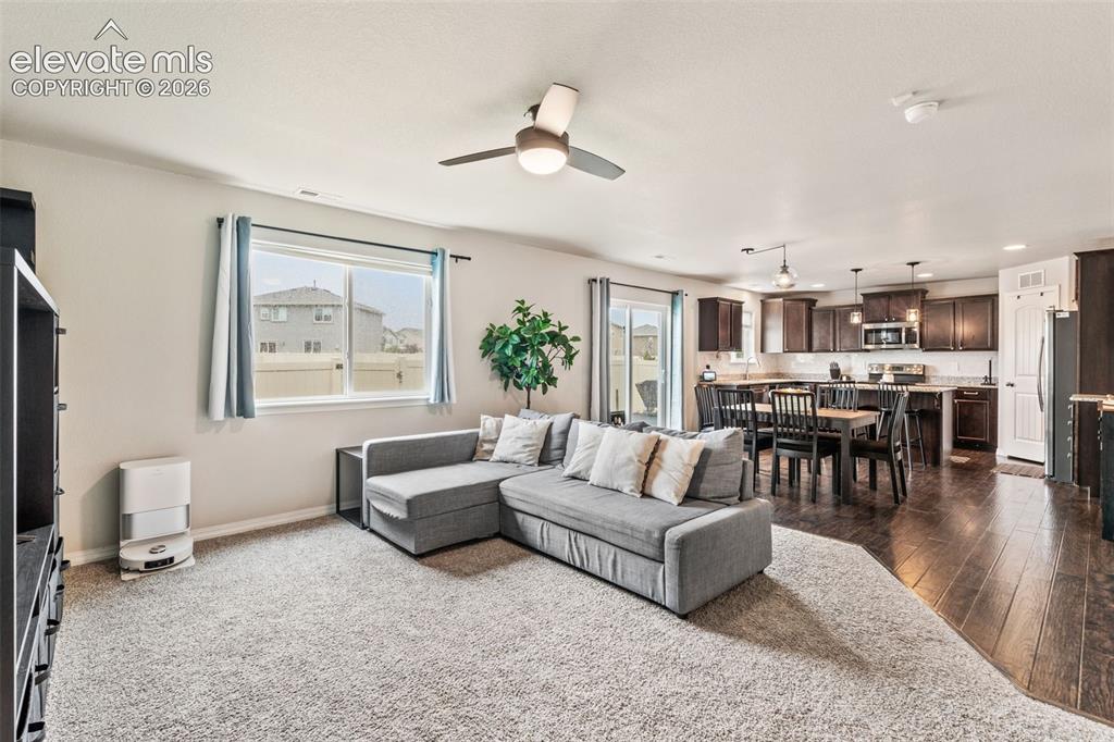 Image 3 of 42: Open-concept living space featuring a ceiling fan, a kitchen with dark cabi