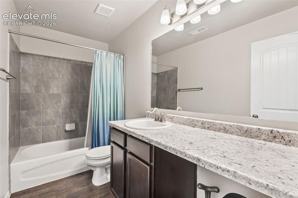 Image 31 of 42: Bathroom featuring a white bathtub, gray tile shower surround, wood-finish