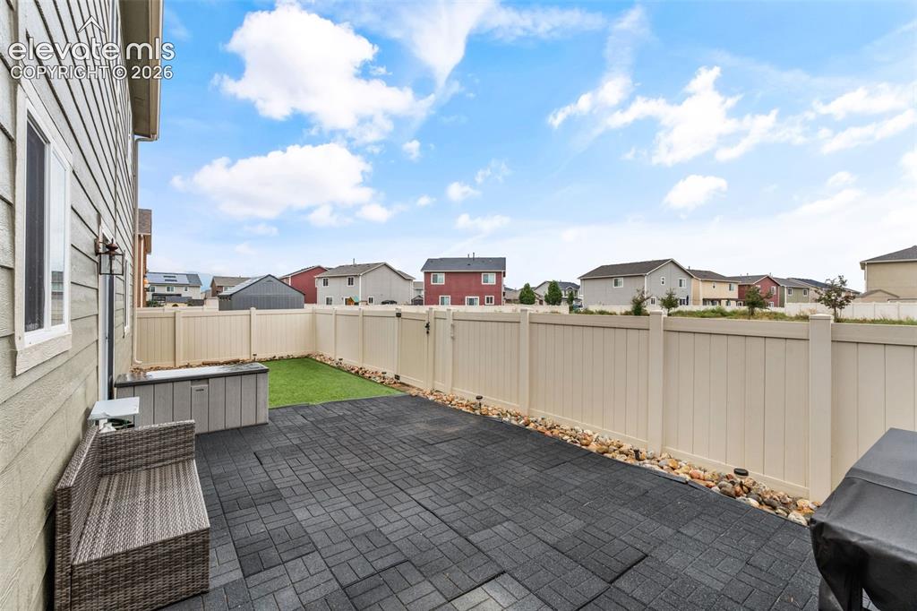 Image 35 of 42: Fenced backyard featuring a paver patio, artificial turf, and decorative ro