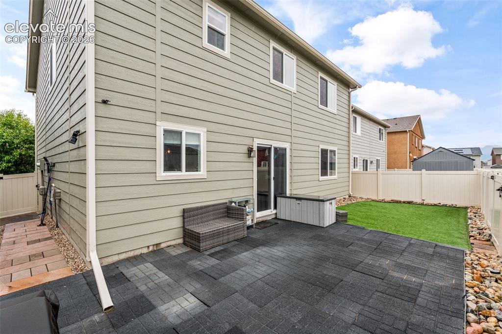 Image 36 of 42: Ground-level patio with dark pavers, complemented by an artificial turf are
