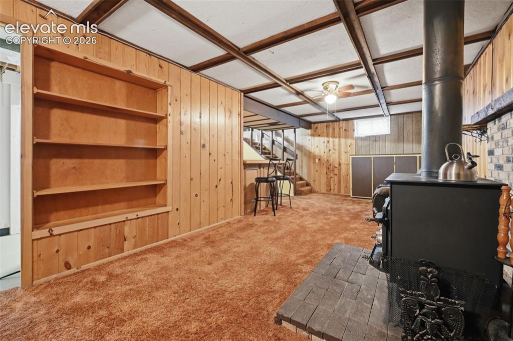 Image 25 of 30: Basement Family Room with Woodburning Stove and Built-ins