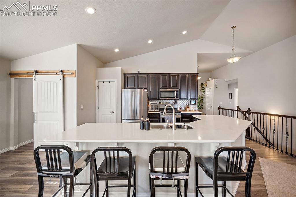 Image 13 of 43: Kitchen featuring a barn door, dark brown cabinets, appliances with stainle