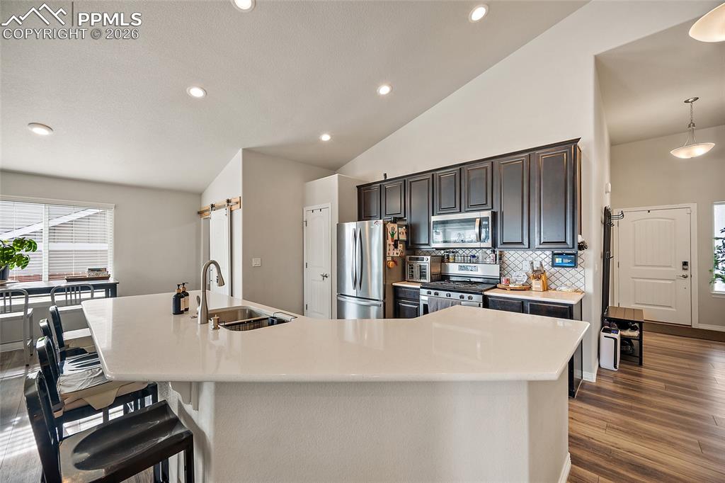 Image 14 of 43: Kitchen with vaulted ceiling, stainless steel appliances, a spacious island