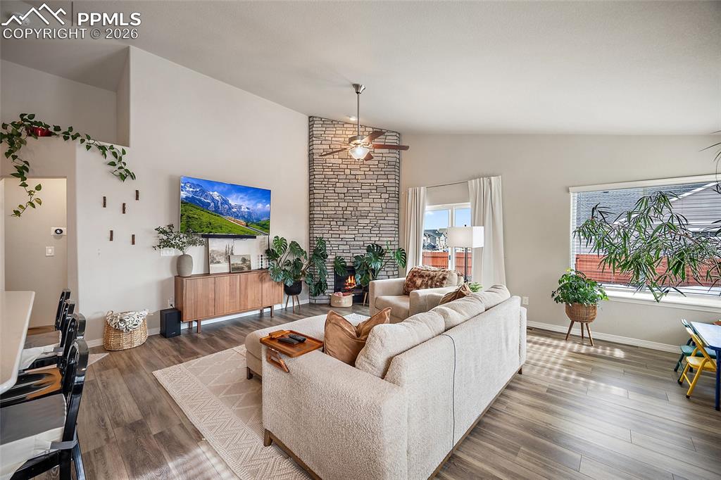 Image 19 of 43: Living area with wood finished floors, high vaulted ceiling, and a fireplac