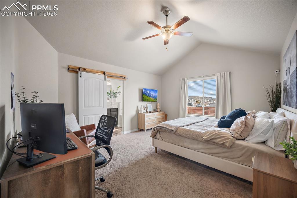 Image 24 of 43: Carpeted bedroom featuring an office area, a barn door, ceiling fan, ensuit