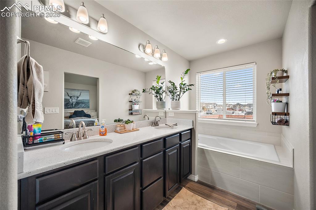 Image 27 of 43: Bathroom with dark wood-style flooring, double vanity, a bath, and ensuite 