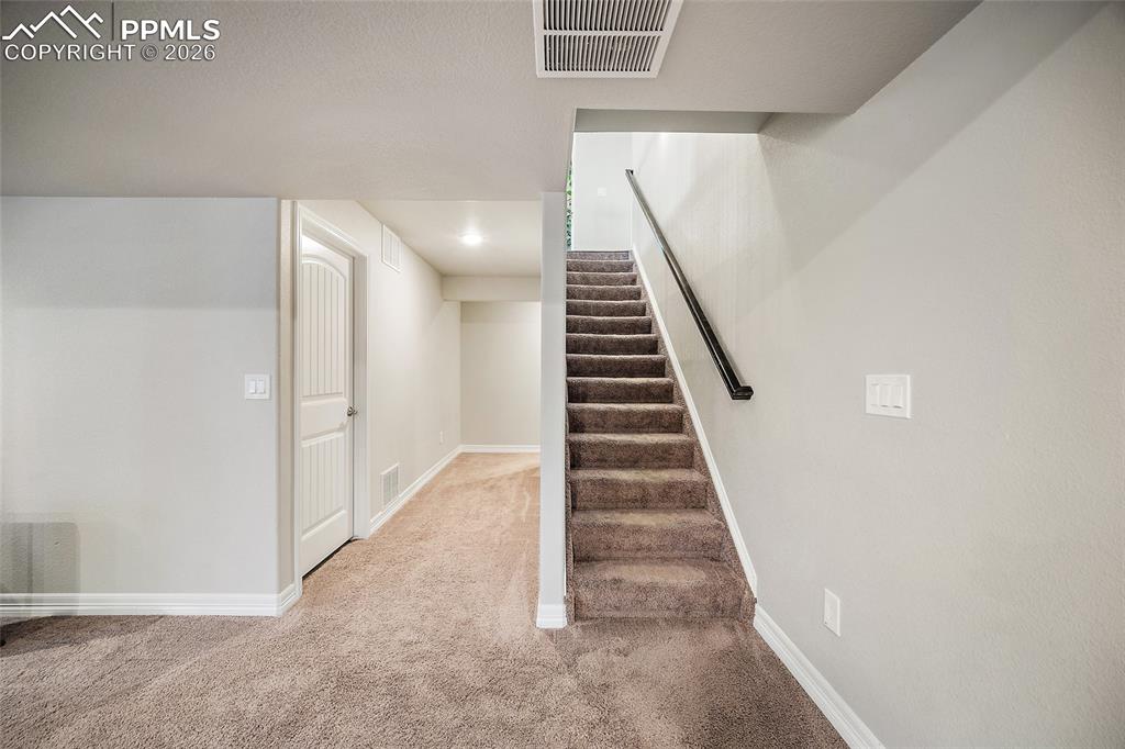 Image 32 of 43: Stairs with baseboards and carpet floors