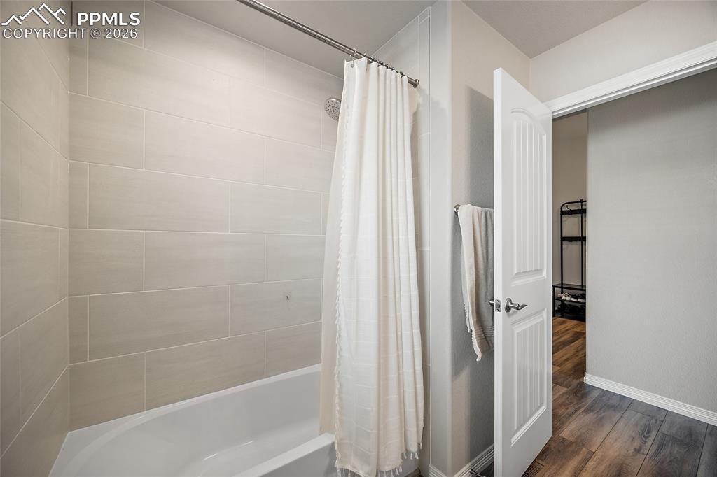 Image 7 of 43: Full bath featuring shower / tub combo and dark wood-style floors