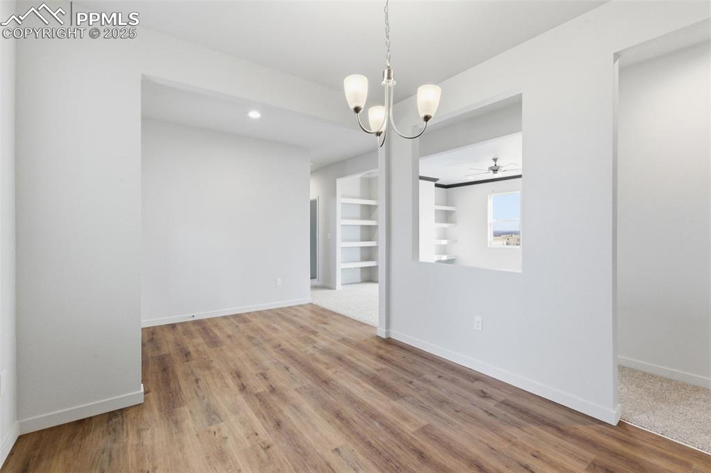 Image 4 of 26: Unfurnished dining area with built in features, light wood finished floors,