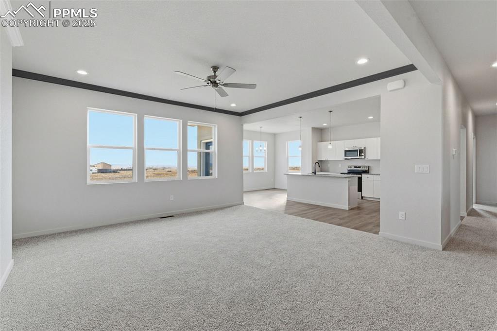 Image 8 of 26: Unfurnished living room featuring light colored carpet, a ceiling fan, and