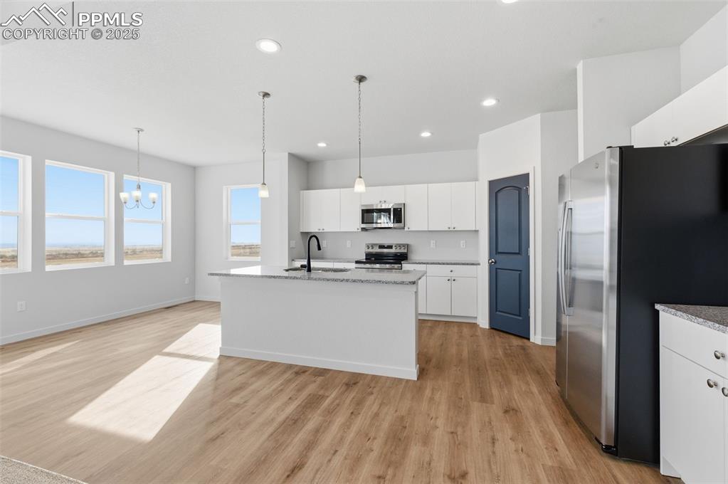 Image 9 of 26: Kitchen with stainless steel appliances, white cabinetry, hanging light fix