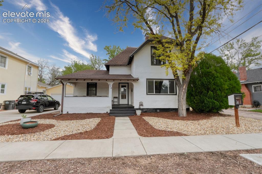 Image 1 of 32: Charming white facade residence featuring a covered front porch, dark trim 