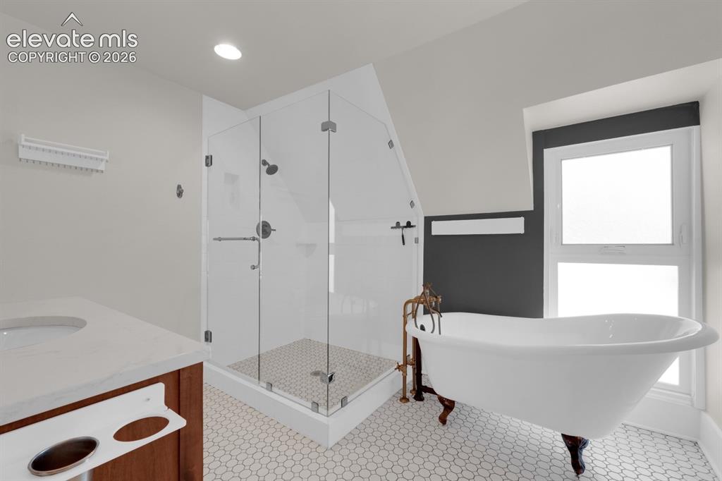 Image 4 of 32: Primary bathroom with glass-enclosed shower & clawfoot tub.