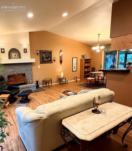 Image 10 of 46: Living area featuring vaulted ceilings, wood-finish flooring, a stone-faced