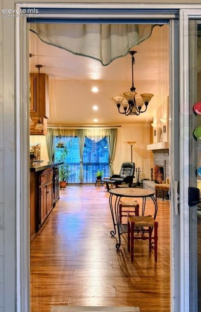 Image 11 of 46: Spacious interior featuring wood-finish flooring, a chandelier with amber g