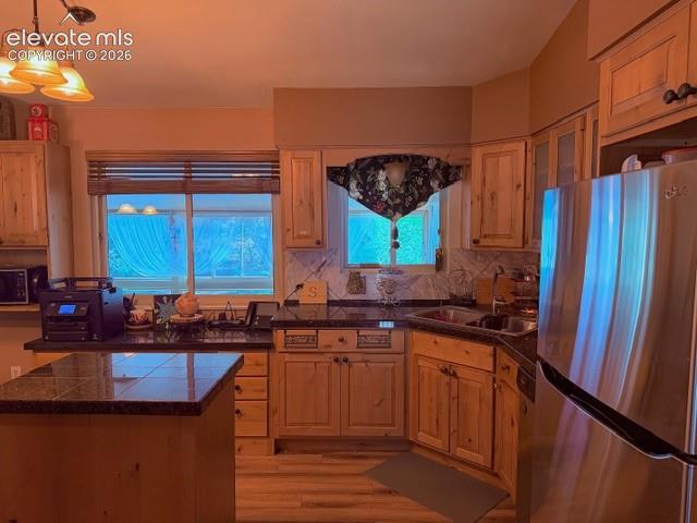 Image 15 of 46: Kitchen featuring natural wood cabinetry, dark granite countertops, and til