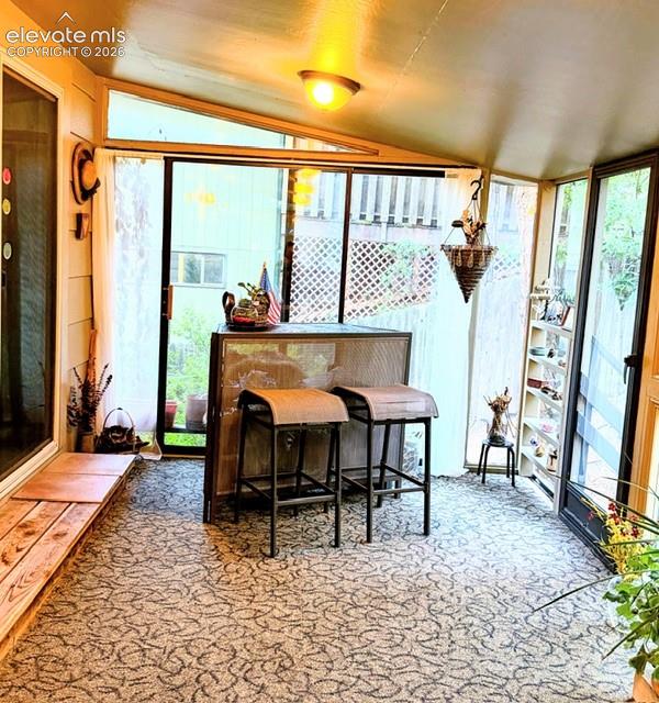 Image 16 of 46: Enclosed sunroom featuring a patterned carpet, sloped ceiling, and multiple