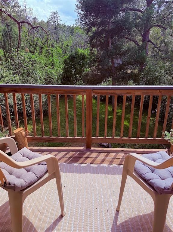 Image 25 of 46: Expansive outdoor deck featuring wood railing and a tree-lined backdrop