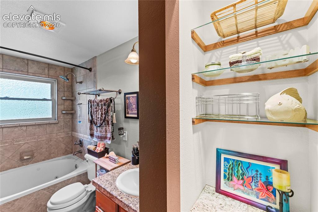 Image 27 of 46: Main bathroom featuring a soaking tub with tiled surround, a window with pr