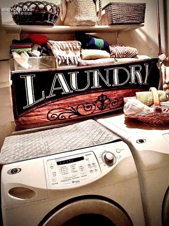 Image 36 of 46: Dedicated laundry space featuring a white front-loading washer and dryer, i