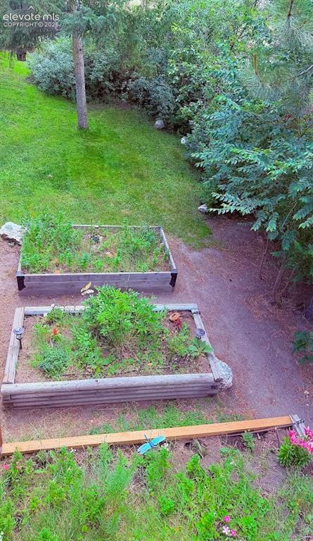 Image 39 of 46: Landscaped exterior featuring two wooden raised garden beds, a gravel path,