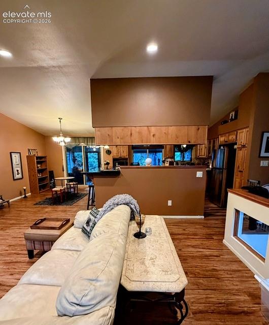 Image 9 of 46: Open-concept living area featuring wood-finish flooring, vaulted ceilings,