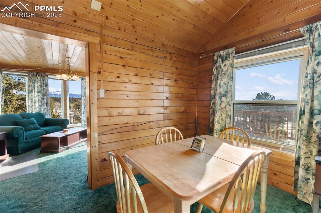 Image 10 of 33: Carpeted dining area with wooden walls, wooden ceiling, lofted ceiling, and