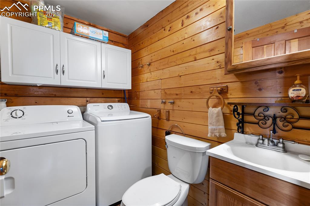 Image 21 of 33: Bathroom featuring wooden walls, washer and clothes dryer