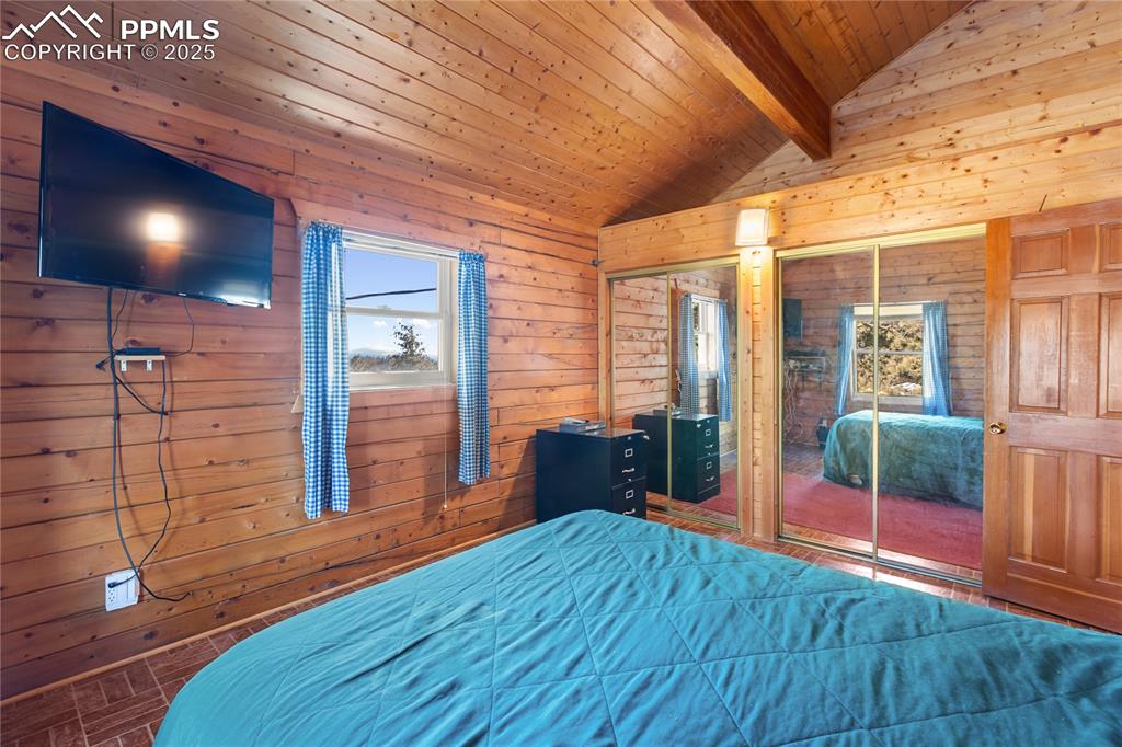 Image 23 of 33: Primary Bedroom with wood ceiling, wooden walls, and multiple closets