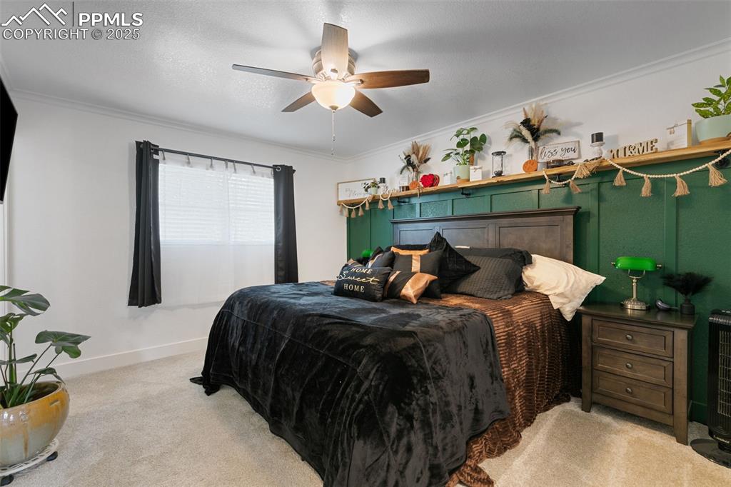 Image 16 of 45: Bedroom featuring carpet floors, crown molding, ceiling fan, and a textured