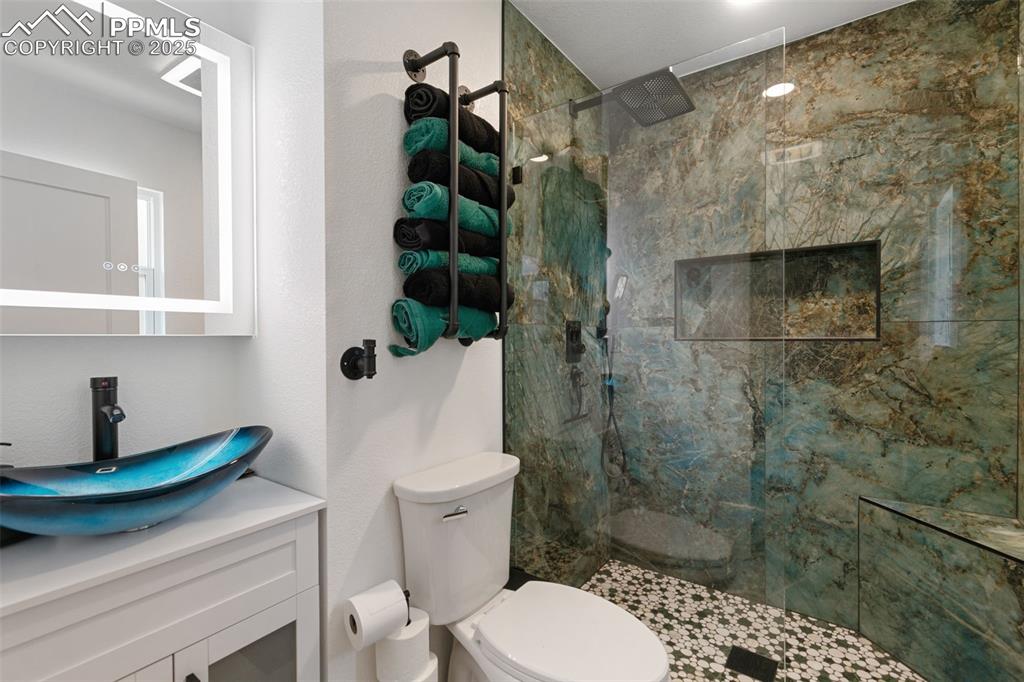 Image 18 of 45: Bathroom featuring a marble finish shower and vanity