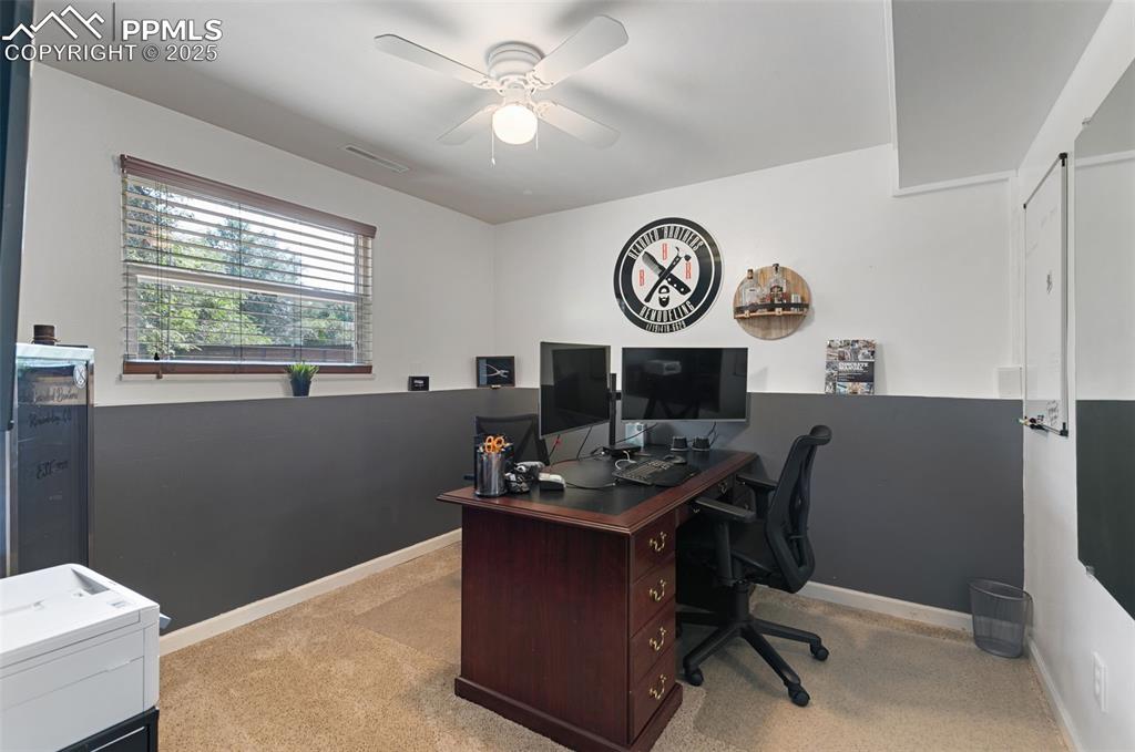 Image 22 of 45: Home office with light colored carpet and ceiling fan