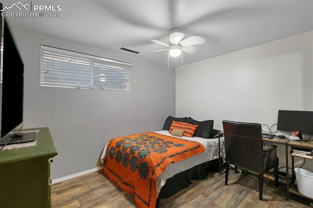 Image 23 of 45: Bedroom with a desk, wood finished floors, and a ceiling fan