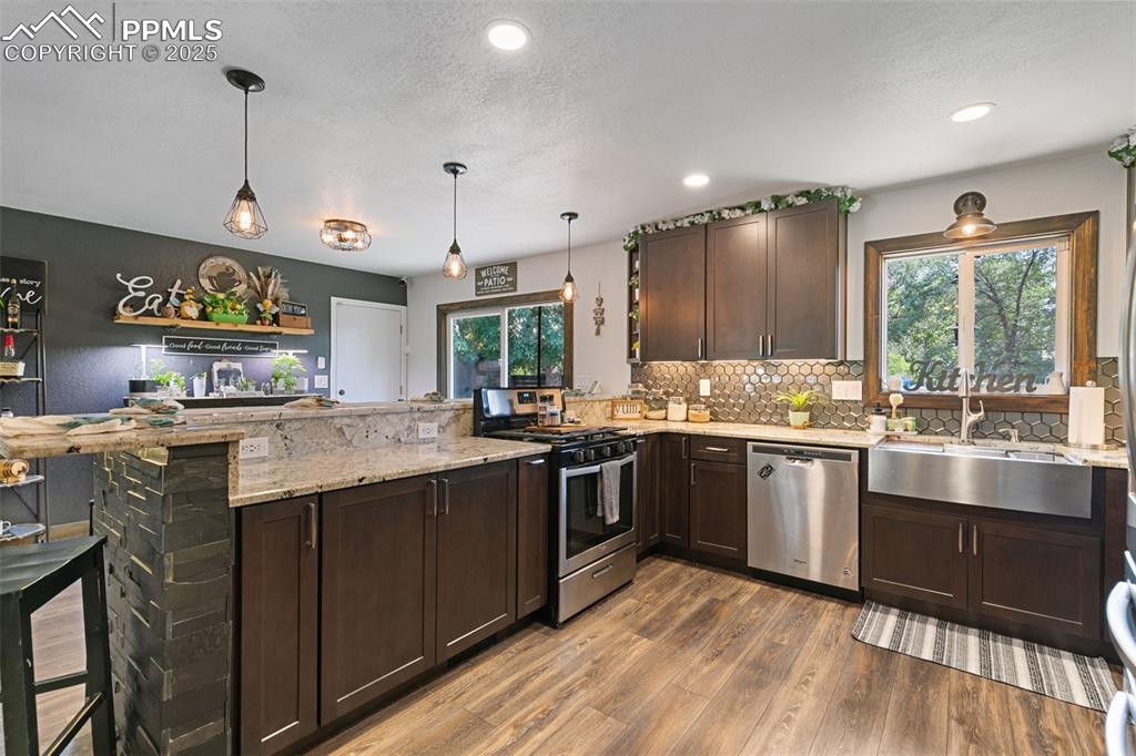 Image 33 of 45: Kitchen featuring dark brown cabinets, a peninsula, appliances with stainle